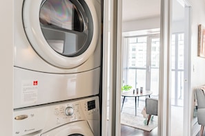 Máquina de lavar e secar Whirlpool Duet de abertura frontal, empilhadas em um apartamento moderno com vista para uma área de jantar e grandes janelas.