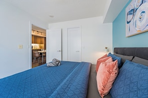 Una habitación de hotel con cama, escritorio y silla, y una kitchenette.