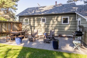 Ein wohnlicher Garten mit Terrasse, Gartenmöbeln und einem Grill.