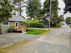 A residential street with houses, a wooden deck, and a grassy lawn. - Cannon Beach Cottage – Walk to Beach & Downtown, Fenced Yard + Dog Friendly (Cannon Beach)