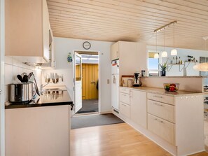 A modern kitchen with wooden cabinets, a built-in oven, and a countertop with various appliances. - "Aarthi" - 300m from the sea by Interhome (Harboøre)