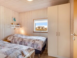 Een slaapkamer met twee bedden, een raam met uitzicht, houten wanden en een kledingkast.