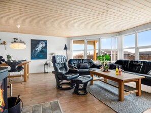 A modern living room with a fireplace, leather sofas, a dining area, and large windows. - "Aarthi" - 300m from the sea by Interhome (Harboøre)