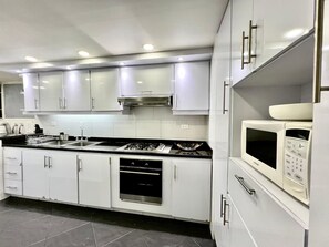 A modern kitchen with white cabinets, stainless steel appliances, and a black countertop. - Excelente ubicación y vista (Bogotá)