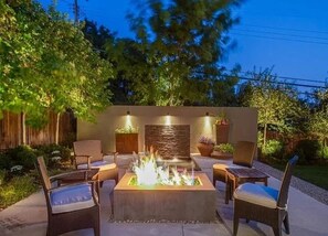 A patio with a fire pit, outdoor furniture, and a stone wall with lighting. - Spacious 4-bedroom house in peaceful Salt Lake City with private patio (Salt Lake City)