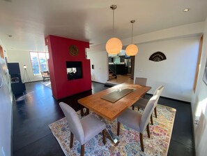 A modern dining area with a wooden table and chairs, a red accent wall, and pendant lighting. - Spacious 4-bedroom house in peaceful Salt Lake City with private patio (Salt Lake City)