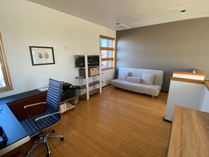 Ein moderner Arbeitsraum mit Schreibtisch, Bürostuhl, Aktenschrank und einer Couch.