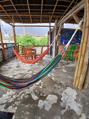 A covered outdoor area with a hammock, wooden chairs, and a concrete floor. - House With Private Pool and bbq (Santa Marta)