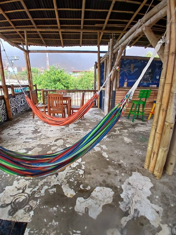 A covered outdoor area with a hammock, wooden chairs, and a concrete floor. - House With Private Pool and bbq (Santa Marta)