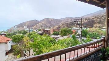 A balcony with a patterned floor, overlooking a residential area with houses and hills.