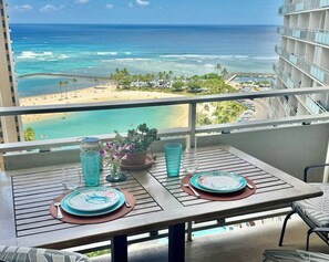 Ein Balkon mit Tisch für zwei Personen, mit Blick auf Strand und Meer.