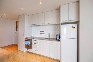 A modern kitchen with white cabinets, a stainless steel sink, and a built-in oven. - Top Floor Loft • 2BR/2BA • Sky Tower & Sea Views (Auckland central)