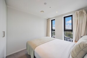 A bedroom with a bed, a window, and a view of the city. - Top Floor Loft • 2BR/2BA • Sky Tower & Sea Views (Auckland central)