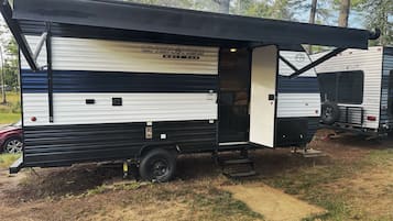 Ein Grauwolf-Campingfahrzeug mit schwarzem Markisenvorzelt, einer Schiebetür und einem einsehbaren Innenraum.