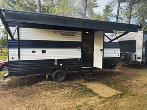 Una caravana Grey Wolf con toldo negro, puerta corrediza y un interior visible.
