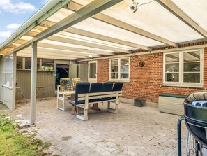 A covered patio area with a bench, a grill, and a brick wall. - "Terese" - 200m to the fjord by Interhome (Farsø)