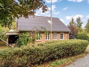 A two-story brick house with a metal roof, a garage, and a well-maintained hedge. - "Terese" - 200m to the fjord by Interhome (Farsø)