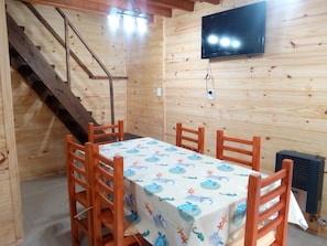 Ein Holzinnenraum mit einem Esstisch, Stühlen, einem Fernseher und einer Treppe.