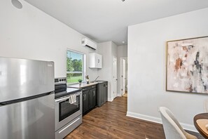 Eine moderne Küche mit Edelstahlgeräten, einem Fenster mit Jalousien und einem Gemälde an der Wand.