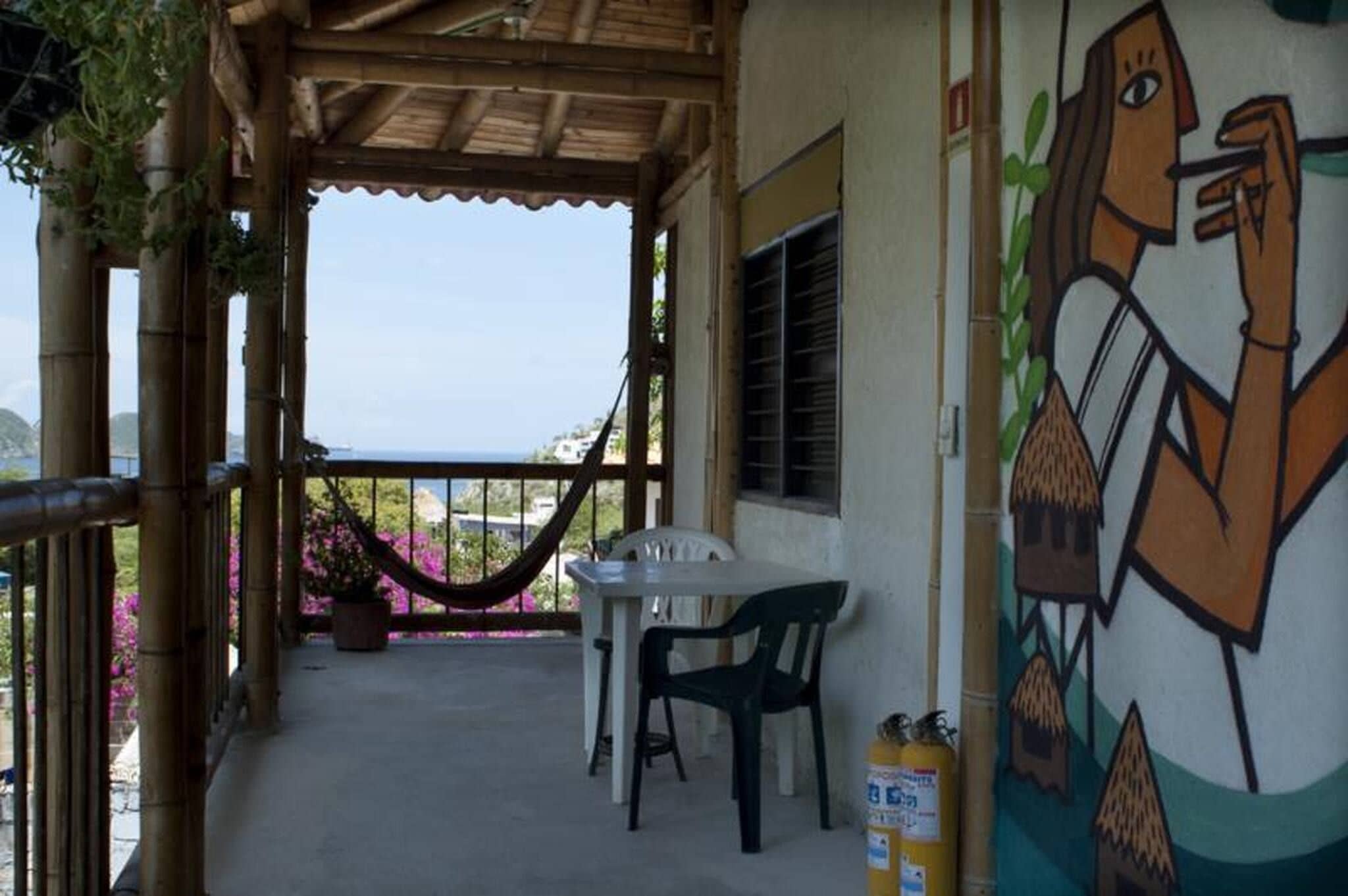 A covered outdoor area with a table and chairs, a hammock, and a mural on the wall.