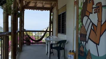 A covered outdoor area with a table and chairs, a hammock, and a mural on the wall.