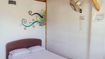 A single bed with a wooden headboard in a room with a bamboo ceiling and a wall-mounted fan.