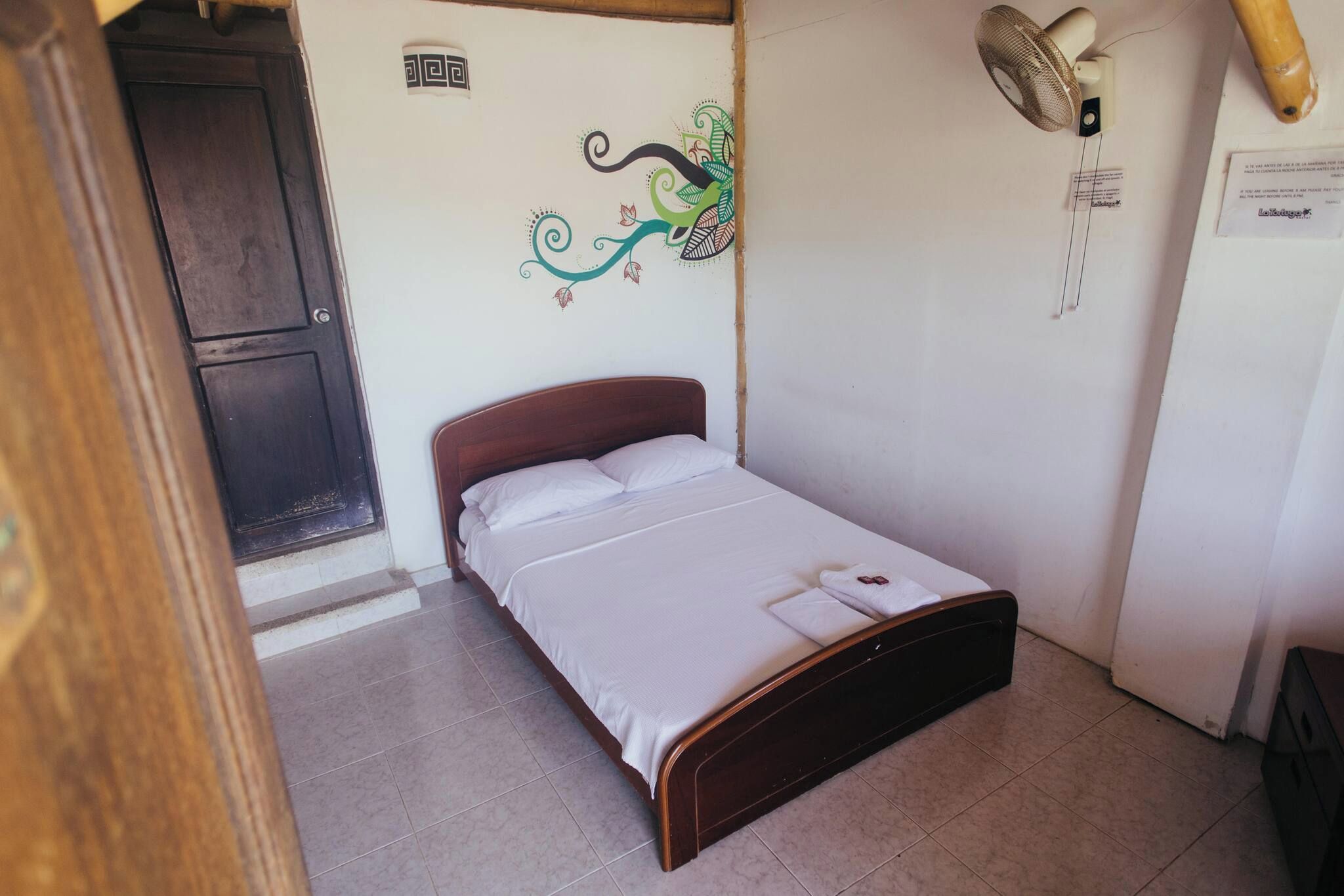 A single bed with a wooden headboard in a room with a tiled floor.