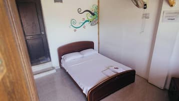 A single bed with a wooden headboard in a room with a tiled floor.