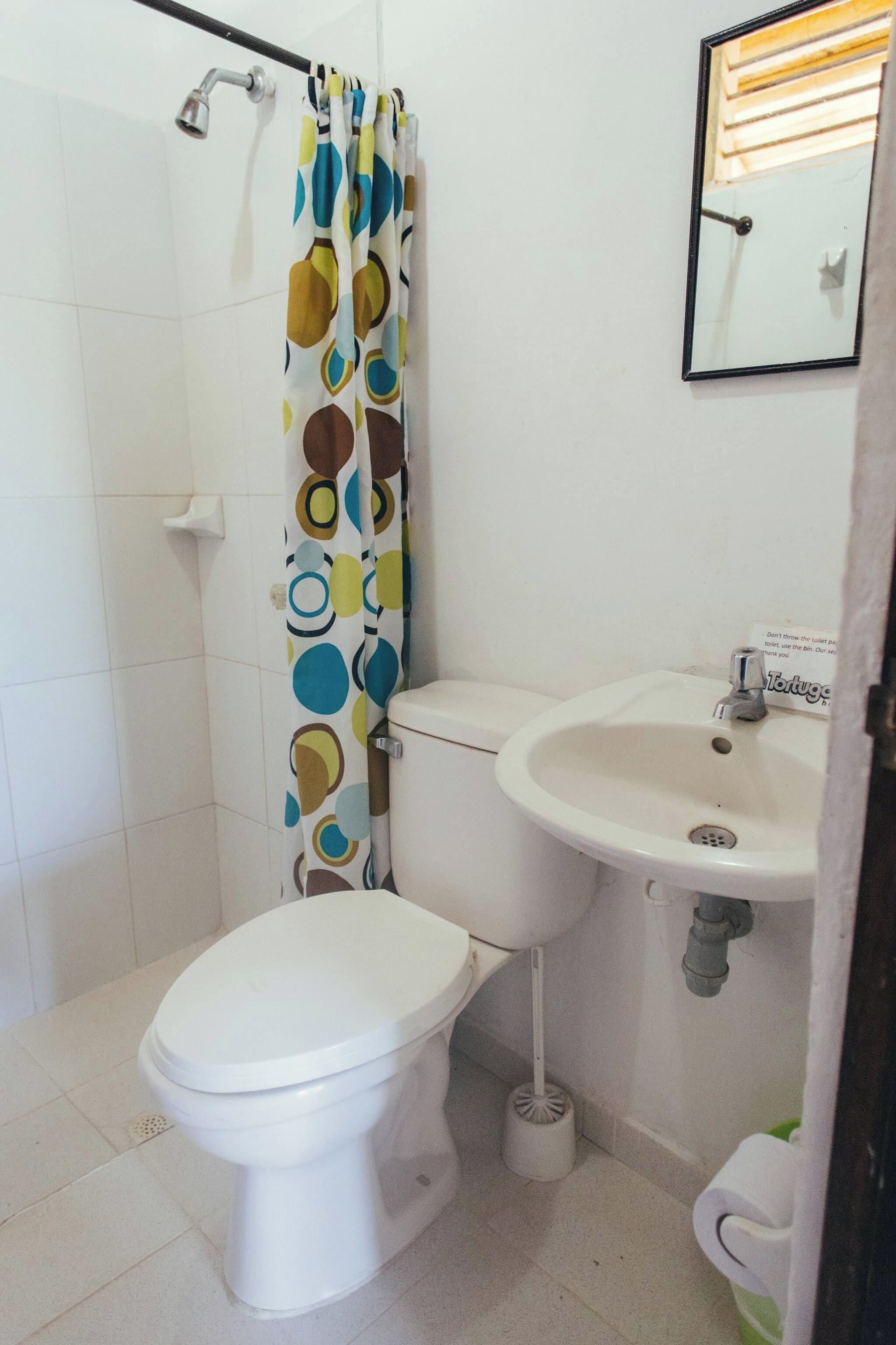 Un baño con inodoro, lavamanos y cortina de ducha con diseño circular.