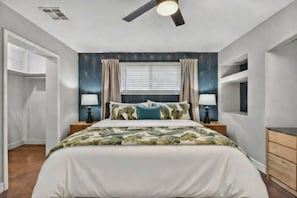 A bedroom with a bed, two bedside tables with lamps, a ceiling fan, a window with curtains, and a built-in shelf. - Mesa Harmony Haus | Bowling, Beats & Bubbles! (Mesa)