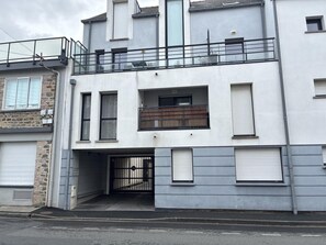 Um edifício de vários andares com entrada para garagem, uma varanda e uma pequena janela.