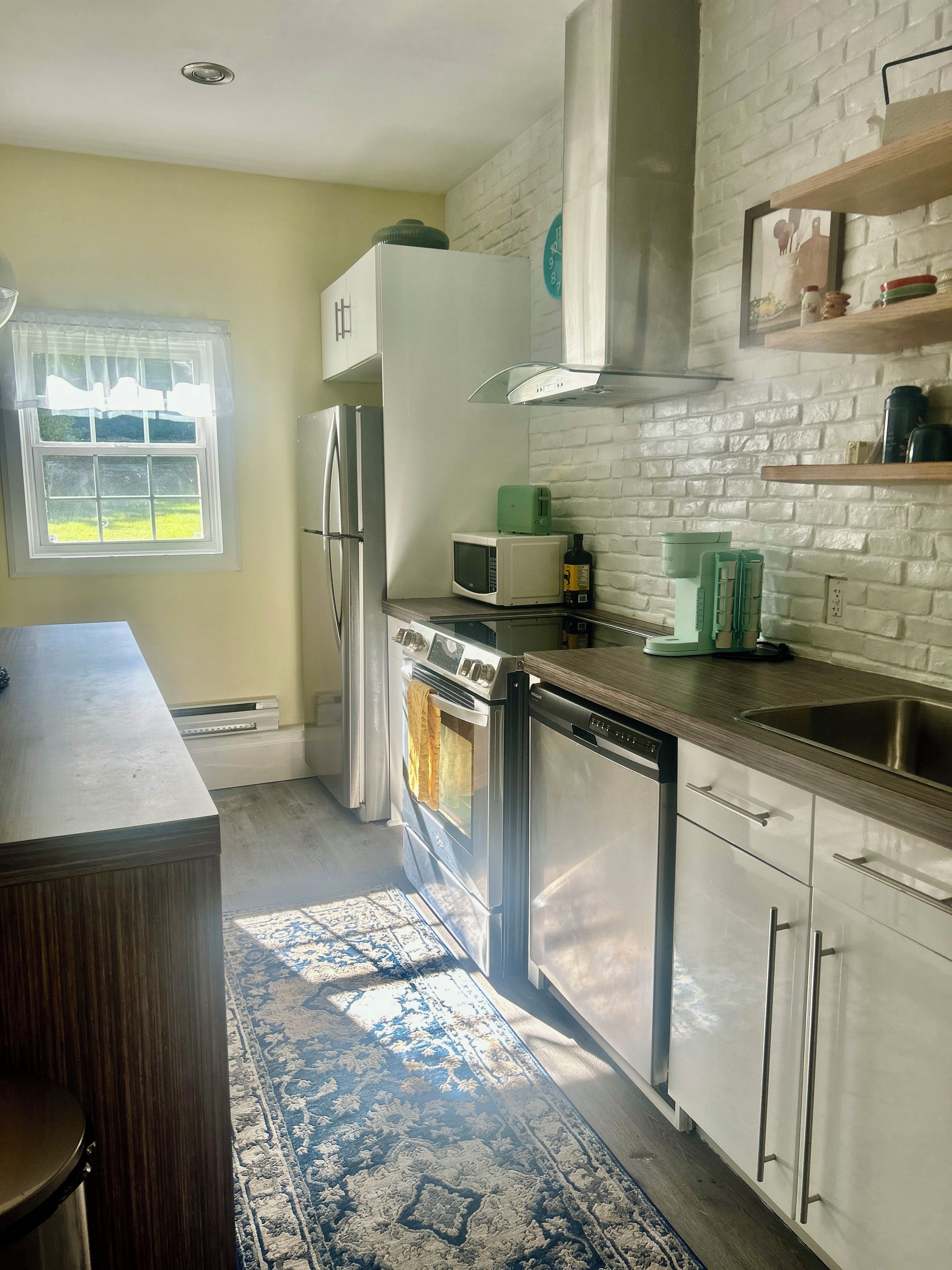 A kitchen with a refrigerator, microwave, oven, and sink.