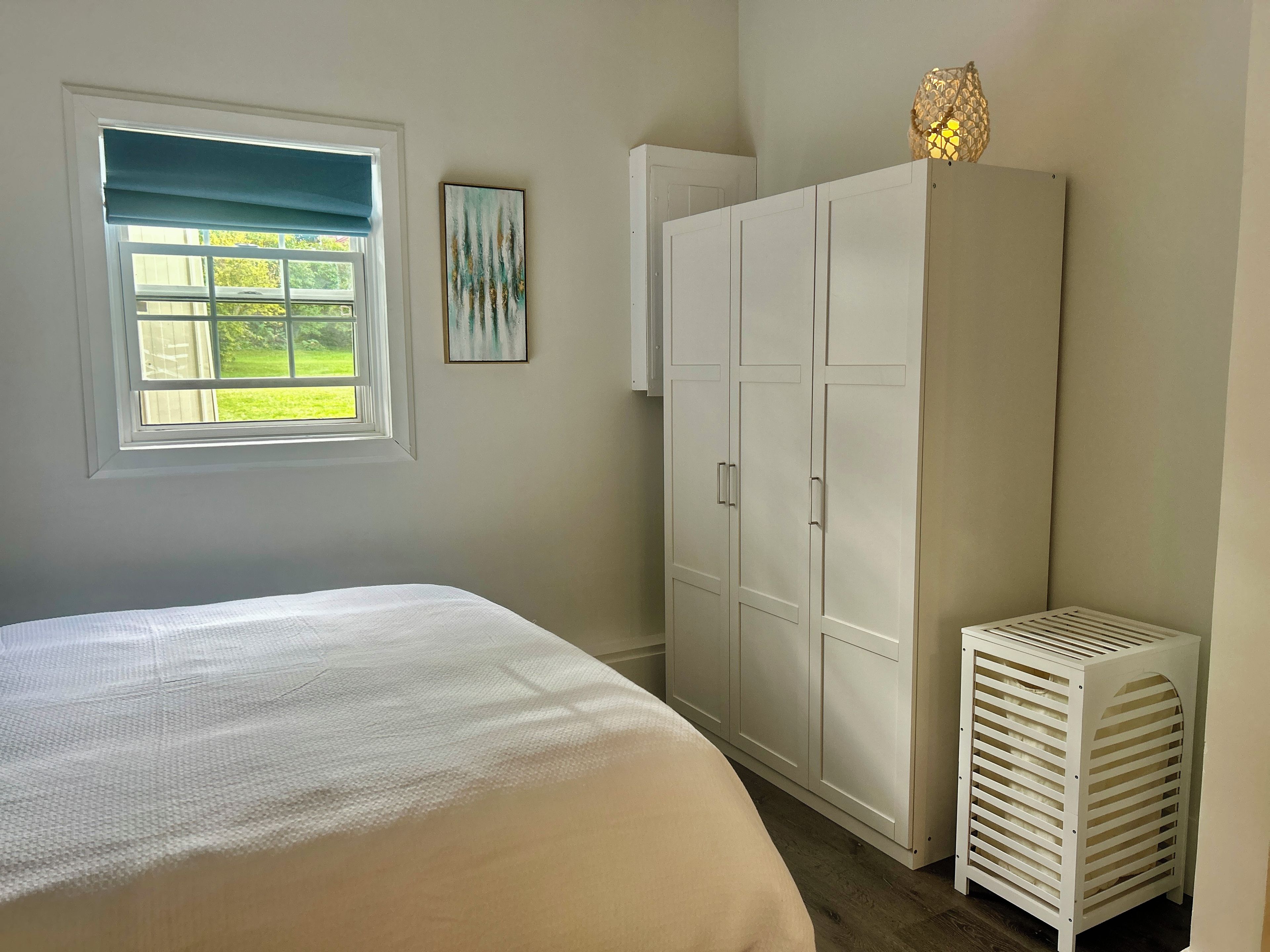 A bedroom with a bed, a window with a view, a wardrobe, and a radiator.