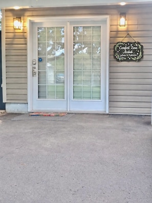 A house with a double door, a doormat, and a sign that reads 'Comfort Zone Airbnb welcome to Fredericton.' - Parkside Comfort Zone (Fredericton)