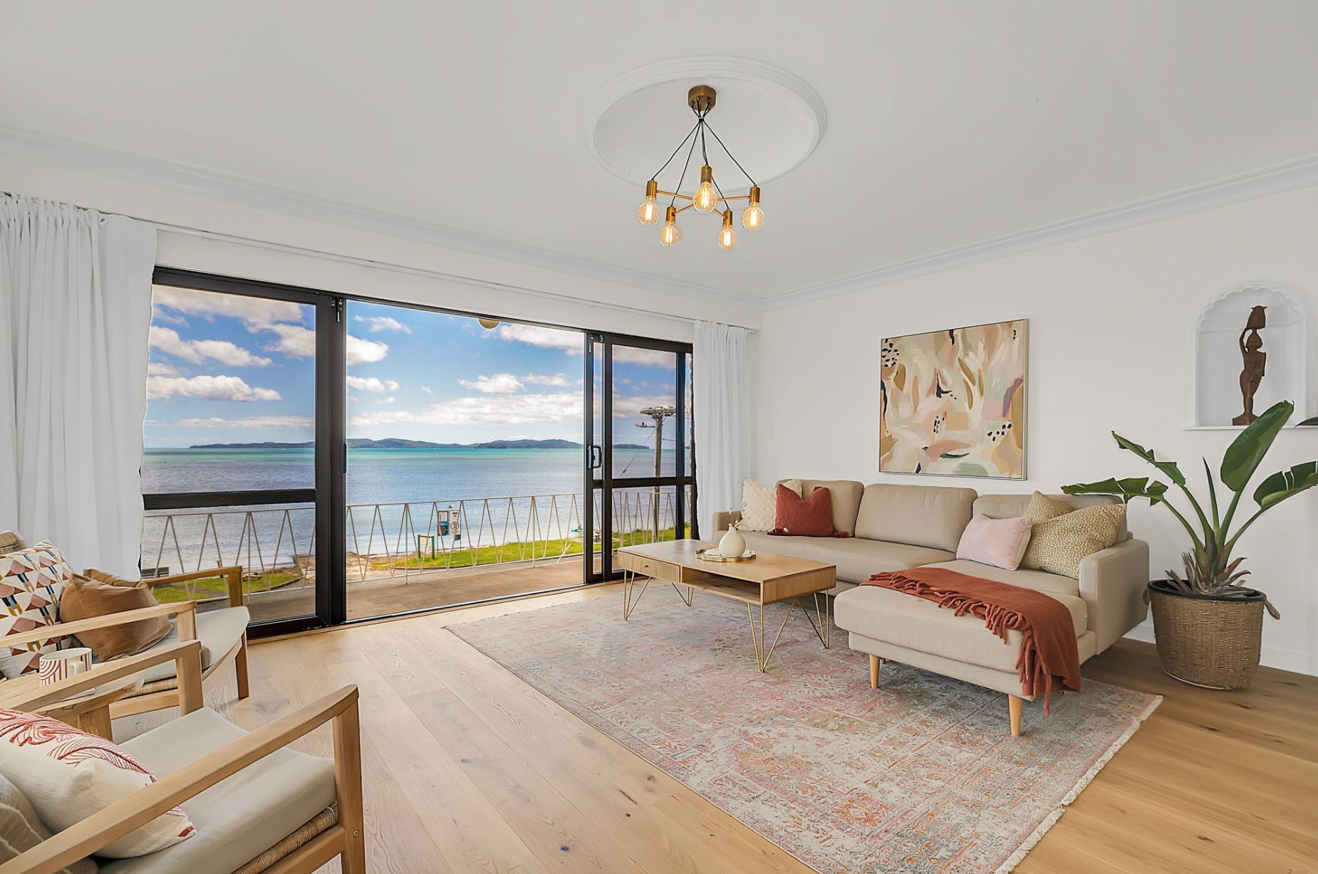 Un salon spacieux doté d’une grande porte-fenêtre coulissante donnant sur un balcon avec vue sur la mer.