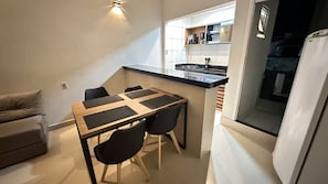 Une cuisine compacte comprenant un coin repas, un canapé et un réfrigérateur.