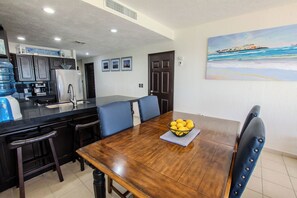 A dining area with a wooden table, blue chairs, and a bowl of lemons. - Sonoran Spa 707E 2 Bedroom 2 Bath (Puerto Peñasco)