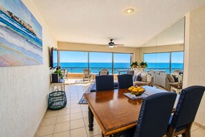 A spacious living area with a balcony overlooking the ocean, a dining table, and a sofa. - Sonoran Spa 707E 2 Bedroom 2 Bath (Puerto Peñasco)