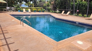 A swimming pool with a metal ladder, surrounded by lounge chairs and potted plants. - Exceptional Family 2-bed/2 bath AC Pool & Garden View on Oceanfront Property (Lahaina)