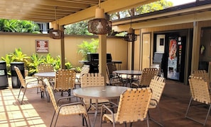 An outdoor patio with wicker chairs and tables, a grill, recycling bins, and a Coca-Cola vending machine. - Exceptional Family 2-bed/2 bath AC Pool & Garden View on Oceanfront Property (Lahaina)