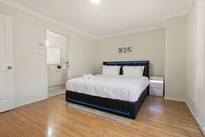 Ein Schlafzimmer mit einem Bett, Nachttischen, einer Tür und einer Wandleuchte.