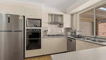 A modern kitchen with stainless steel appliances, a built-in oven, and a dishwasher.