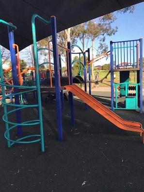 A playground with a slide, climbing structures, and a covered area. - The Wattle House - Your Home Away From Home (Sydney)