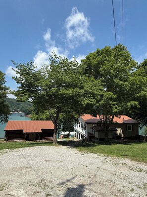 A lakeside property with a gravel driveway, a wooden cabin, and a house with a porch. - Norris Lakefront Retreat — House + Cabin — Sleeps 18 (LaFollette)