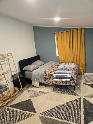 Ein Schlafzimmer mit einem Bett, einer Holzleiter, einem Nachttisch und einem gemusterten Teppich.