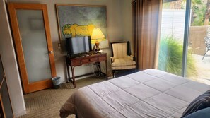Ein Hotelzimmer mit einem Bett, einem Schreibtisch mit Lampe, einem Stuhl und einem Gemälde an der Wand.