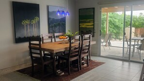 Ein Essbereich mit einem Holztisch, Stühlen, einer Vase mit Blumen und zwei Bildern an der Wand.