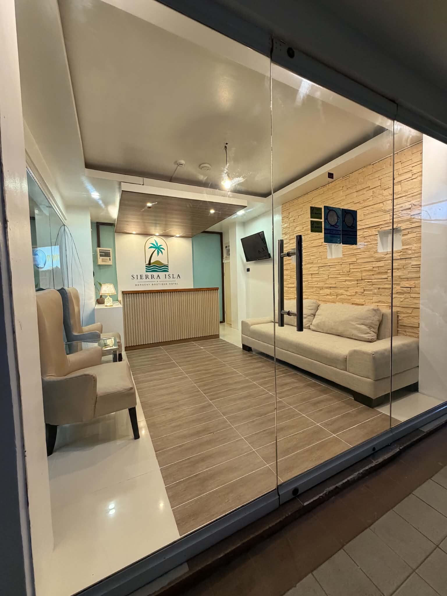 A reception area with a logo, a sofa, a chair, and a wall with a wooden texture.