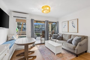 Ein modernes Wohnzimmer mit einer Couch, einem Couchtisch, einem Fernseher und einem Balkon mit Blick.