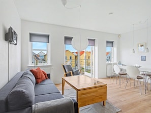 Un salon moderne comprenant un canapé, une table basse et un coin repas avec des chaises et une table.